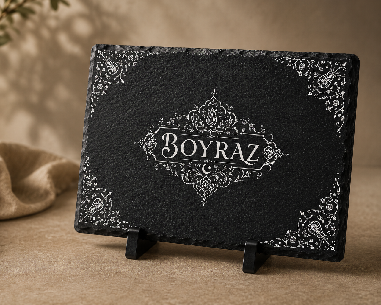 Black decorative box with 'Boyraz' branding on a wooden surface with a plant and cloth in the background.